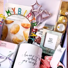 A fun and girly birthday hamper with a 'chase what you seek' mug, a 'Happy Birthday' headband, face masks, and Ferrero Rocher chocolates.