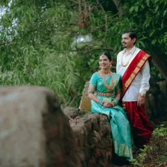 A beautifully composed portrait of the couple in a natural setting. The bride is seated while the groom stands, creating a classic and elegant pose.