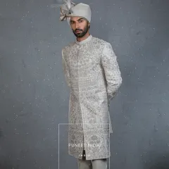 An ivory-toned silk sherwani adorned with Resham embroidery, where a floral and vine jaal meets geometric lattice patterns. This is a regal harmony of tradition and modern elegance, crafted for the big day.