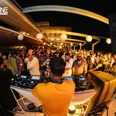 A wide-angle view of the rooftop party. You can see the open sky and the crowd fully immersed in the sundowner experience.