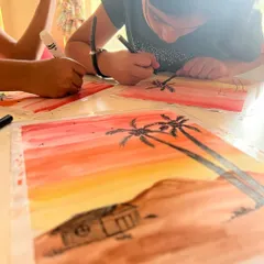 Adding the final touches. After painting the watercolor background, the kids use black markers to draw silhouettes, learning about foreground and background.