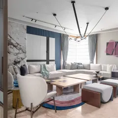 A view of the living area showcasing the interplay of textures and light. The design combines a plush sectional sofa, a unique split coffee table, and a sculptural light fixture to create a dynamic yet harmonious environment.