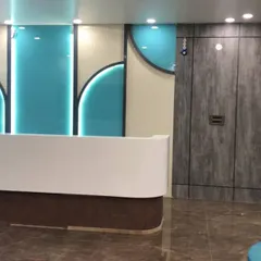 The finished reception area of the school, featuring the custom white desk against a backdrop of teal glass and wood-look panels. The design is clean, modern, and welcoming for students, parents, and staff.