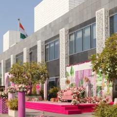 The main stage for a poolside Haldi ceremony, decorated in shades of pink with a beautiful floral backdrop and modern lattice panels.