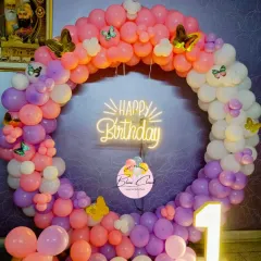 A beautiful butterfly-themed balloon ring for a first birthday. We used a mix of pink, purple, and orange balloons, accented with butterflies and a neon "Happy Birthday" sign.
