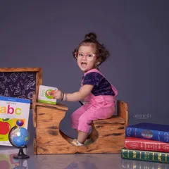 Back to school! A fun and creative theme with a little girl at a miniature school desk, surrounded by books, a globe, and an alphabet chart. It's a perfect way to capture their curious spirit.