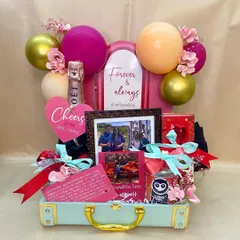 Celebrating love stories is one of my greatest joys. This custom trunk was designed for a special couple, complete with personalized photos, celebratory champagne, and a balloon arch to mark their 'Forever & Always' moment.