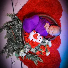A precious newborn portrait, with the baby sleeping peacefully in a basket on a large, fluffy red heart. I use soft textures and props to ensure your baby is comfortable and safe.