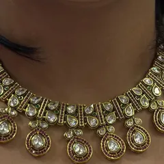 A close-up of a beautiful Polki necklace with ruby-coloured drops. The fine craftsmanship and antique finish give it a very rich and authentic look.