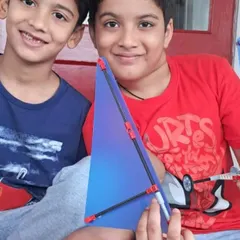 Two brothers proudly show off the wind-powered car they built together, a great example of teamwork and creative engineering.