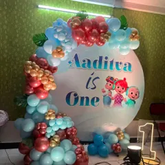 This Cocomelon theme is a favorite for first birthdays. The setup includes a custom circular backdrop with the birthday boy's name, a vibrant balloon garland, and a light-up marquee number '1' to make the milestone special.