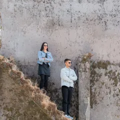 A stylish, coordinated shot of a couple in denim jackets against rustic ruins. This image has a cool, relaxed vibe, showing how nature can be a backdrop for modern and fashionable portraits.