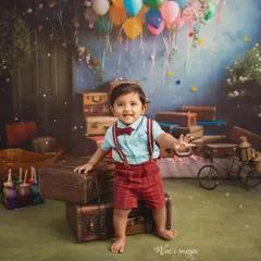 Reaching for new adventures. This joyful shot captures a toddler's excitement amidst a backdrop of vintage suitcases and colorful balloons, symbolizing the journey of growing up.