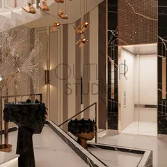 This view highlights the intricate details of the lobby, including a sculptural black marble basin, a feather-like art piece, and another cascading chandelier, all contributing to the grand experience.
