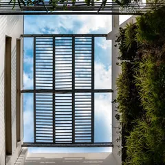 A view looking up at the bamboo pergola and green wall at the building's entrance. These elements provide shading on the south-west facade and create a dramatic, nature-filled entry experience.