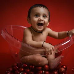 Look at that happy face. This little boy's excitement is contagious. For this themed shoot, we used a clear bathtub prop and festive red ornaments for a fun and unique baby portrait.