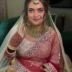 A close-up of the bride's face, framed by her beautiful updo and delicate nath. The hairstyle is designed to balance the entire look.