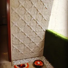 We designed this apartment entrance to be both welcoming and stylish. It features 3D stone cladding on the wall, a border of white pebbles, and a patch of artificial grass, creating a multi-textured and modern first impression.