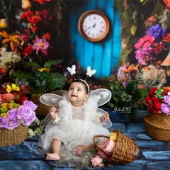 Looking up in wonder, this little butterfly fairy is absolutely captivating. The colorful, flower-filled backdrop creates a vibrant and joyful scene.