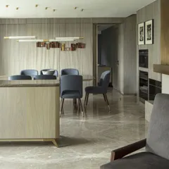 A wider view of the Jor Bagh dining area, showing its seamless flow into the formal living space. The material palette of wood, marble, and brass creates a cohesive and luxurious feel.
