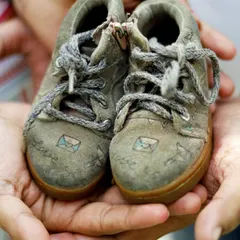 A close up shot focusing on a pair of tiny baby shoes held in the hands of the expectant parents, a classic and symbolic maternity photo.