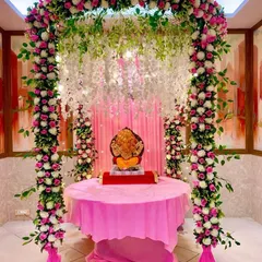 An elaborate and beautiful floral mandap for Ganpati, using a full arch of artificial pink and white roses and hanging wisteria to create a grand and festive look.