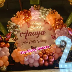 For this "Two Cute Today" second birthday, I used a modern color palette of rose gold, silver, and peach balloons. The decor features a custom round backdrop, a neon sign, and a large marquee number '2'.