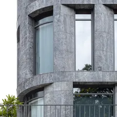 The curved corner of The Afyon Pavillion, clad in Afyon Grey marble. This detail demonstrates the technical skill required to apply a rigid material to a fluid form, resulting in a sophisticated and elegant facade.