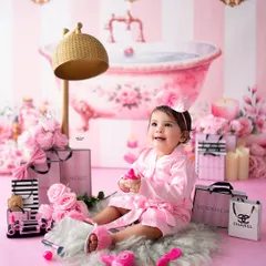 It's a spa day! This adorable baby is all smiles in her pink satin robe, surrounded by everything needed for a day of pampering. These creative sessions are always a hit.