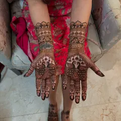 A beautiful display of full bridal henna, with peacocks on the palms and matching intricate patterns on the feet. The design is dense and detailed, perfect for a traditional bride.
