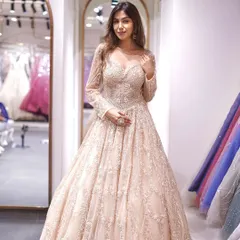 A full-length view of a breathtaking beige gown with long sleeves. The intricate, all-over embellishments create a look of pure luxury and sophistication, perfect for a grand reception.