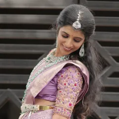 A side profile of a bride showcasing her elegant American Diamond jewellery set. You can see the sparkle of the long earrings and maang tikka, which perfectly complement her lavender silk saree and embroidered blouse.