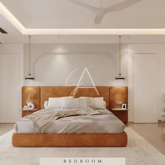 In this bedroom design, a warm, tan leather-upholstered bed creates a rich and inviting focal point. The room is designed with soft, indirect lighting from the ceiling cove and bedside pendants to enhance the cozy, luxurious feel.