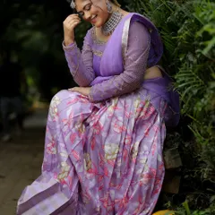A candid, happy moment from a photoshoot. The model wears a modern silver-finish choker that pairs beautifully with this floral lavender saree.