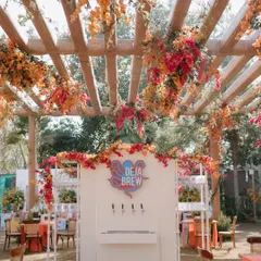 A carnival-themed Mehendi featuring a "Deja Brew" station with beer on tap, set under a pergola dripping with bougainvillea.