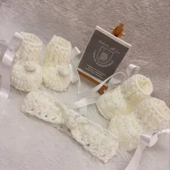 This complete baptism set includes soft white booties and a matching headband. Both pieces are detailed with delicate crochet roses and tiny pearls for an elegant finish.
