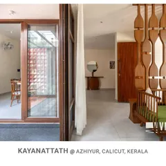 A look from the living space towards the entrance at Kayanattath House, where the open layout and wooden screen partition maintain a visual connection to the courtyard and other areas.