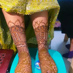 A full bridal foot mehandi design that extends up the legs. The pattern is dense and intricate, perfect for a bride.