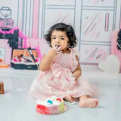 A stylish cake smash with a Barbie theme. This little girl is having her first taste of cake, a sweet moment captured against the chic illustrated backdrop.
