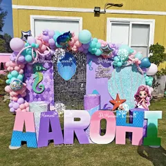 A close-up of the vibrant outdoor mermaid stage, showing the detailed props like the seahorse, starfish, and the custom-painted marquee letters.