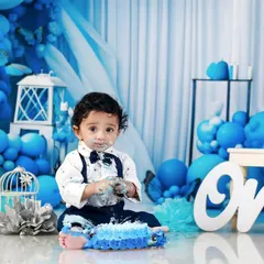 The aftermath of the fun! The birthday boy looks at the camera with cake on his face, surrounded by his blue-themed party decor.