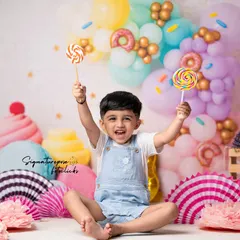 Three years old and sweet as candy! This little boy is having the time of his life in our candy-themed birthday shoot, complete with giant lollipops and a colorful balloon backdrop.
