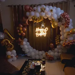A cozy and elegant 13th birthday decoration at home. The ring is decorated with white, gold, and rose gold balloons, with a 'Happy Birthday' neon sign in the center.