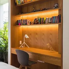 A compact and highly efficient study nook built into a bedroom. We used warm wood for the desk and shelving, with integrated LED lighting under the shelves to create a bright and pleasant workspace.