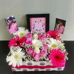 A perfect floral gift box for a loved one. This arrangement is bursting with pink and white gerberas, roses, and baby's breath, and includes a mini quote frame and personal photos for an extra thoughtful touch.