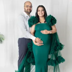 A classic couple portrait for your maternity album. The partner stands supportively behind the mom-to-be, both gently holding the baby bump. It’s a timeless pose that symbolizes unity and anticipation.