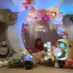 I can bring any cartoon theme to life for your child's first birthday. This grand Lion King setup includes character cutouts, a large crescent moon prop, a light-up number '1', and a custom neon 'Happy Birthday' sign.