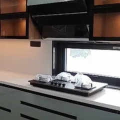 A close-up of a completed kitchen from another project. This view shows the under-cabinet lighting, sleek countertop, and glass-fronted upper cabinets, all elements of a modern, functional kitchen design.