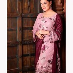 An elegant portrait of Sherleen Dutt in a beautifully embroidered salwar suit. The rustic wooden door provides a warm, textured background that complements the traditional outfit.