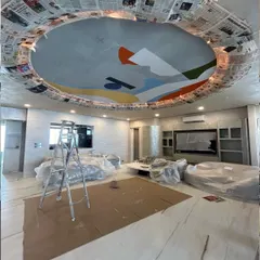 The ceiling mural in progress. The room is protected as we work overhead, slowly filling in the large, colorful shapes that represent the energy of Mumbai.